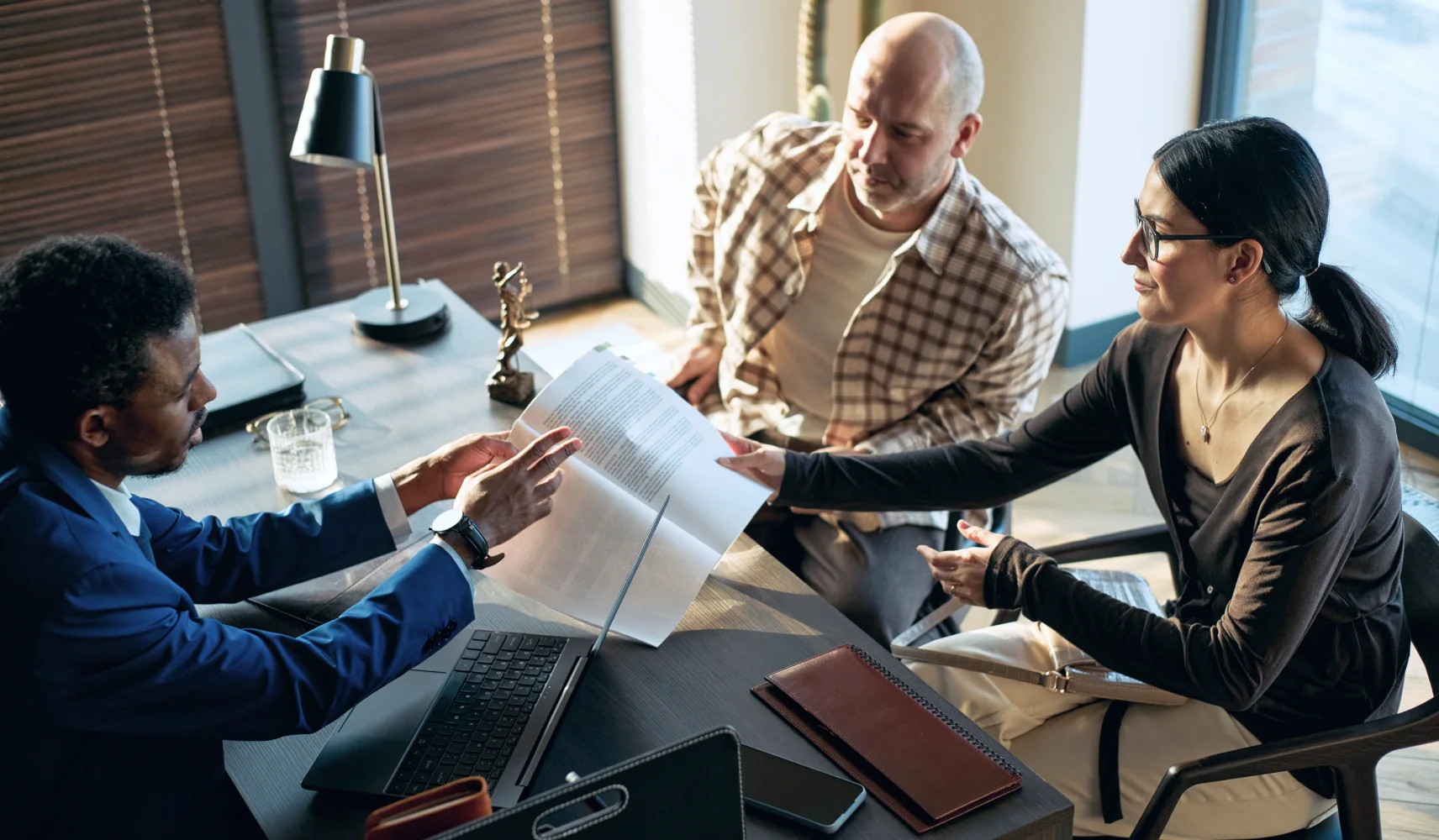 An attorney reviewing documents with two clients across a desk