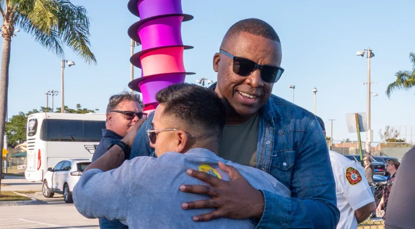 Two men embracing at an outdoor community event